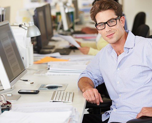 Man Working At Desk In Busy Creative Office